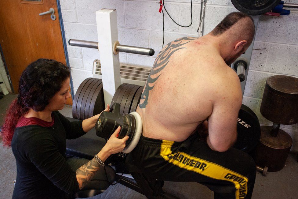 Nina using a car polisher on Mikey's back