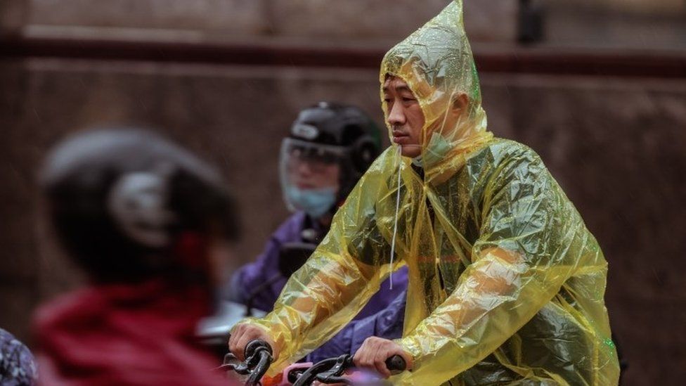 Man in poncho on bike in Shanghai