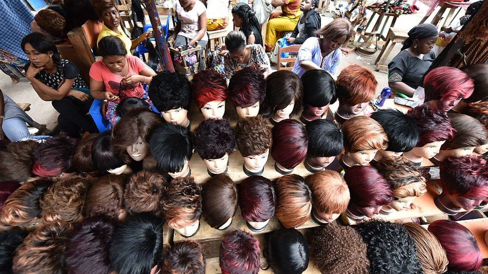 Women make wigs with artificial hair in a wig shop in a market in Abidjan, Ivory Coast