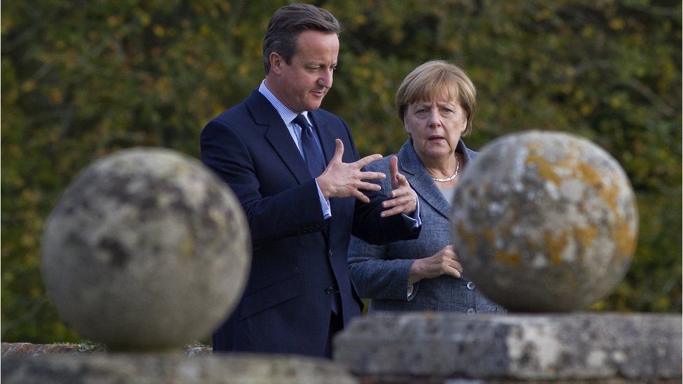 David Cameron and Angela Merkel in British Prime Minister David Cameron walks around the rose garden with German Chancellor Angela Merkel (R) during a meeting at Chequers, the Prime Minister's country residence on October 9, 2015 near Aylesbury, Buckinghamshire, United Kingdom