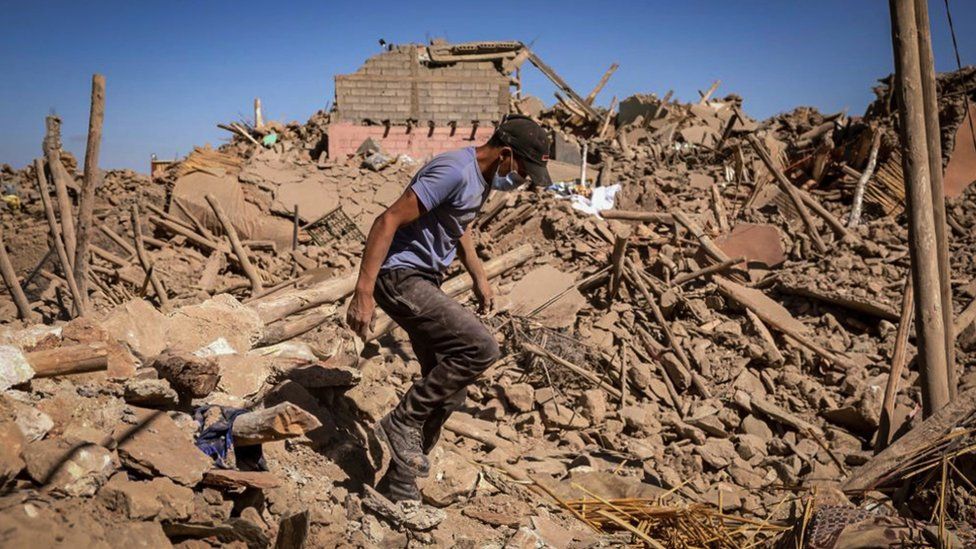 A man walks through the rubble of a ruined village