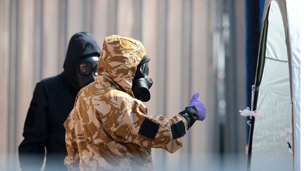 Emergency workers in protective suits search around a potentially contaminated site
