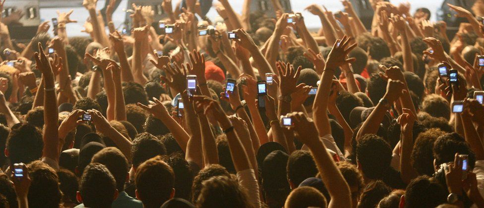 Concertgoers holding up mobile phones