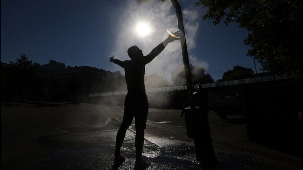 Мужчина охлаждается под разбрызгивателем воды в жаркий летний день в Вене, Австрия, 30 июля 2020 года.