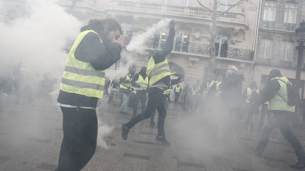 Image shows a protester throwing a tear gas canister.