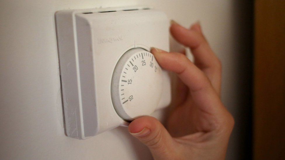 A person using a central heating thermostat