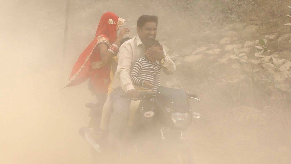 Indian family on motorbike in heavily polluted air