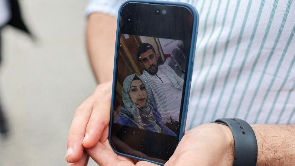 Syrian Kassam Abozeed, 34, who says his wife Israa and brother-in-law were onboard a boat with migrants that capsized at open sea off Greece, demonstrates a photo of him and his wife, at the port of Kalamata, Greece, June 15, 2023