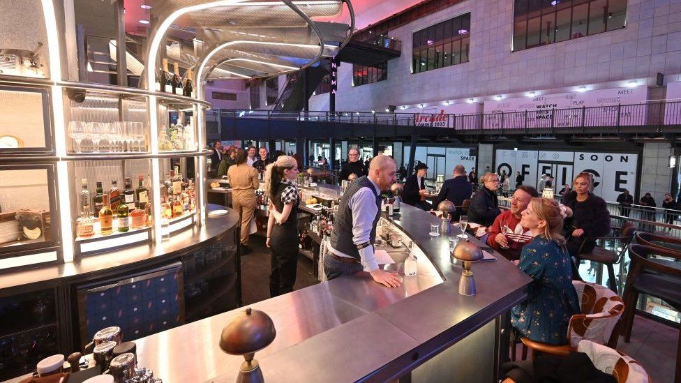 People talking to a bartender at a bar within the power station