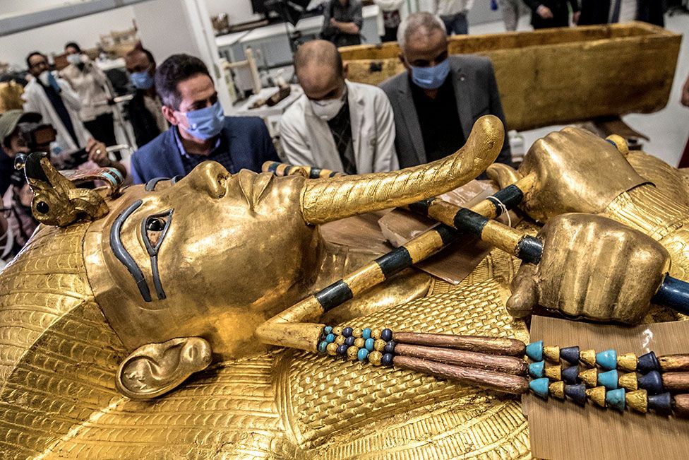 The golden sarcophagus of the ancient Egyptian Pharaoh Tutankhamun lies in the restoration lab as workers look on