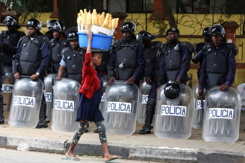A woman walks past police officers in Luanda, Angola, on 25 August.