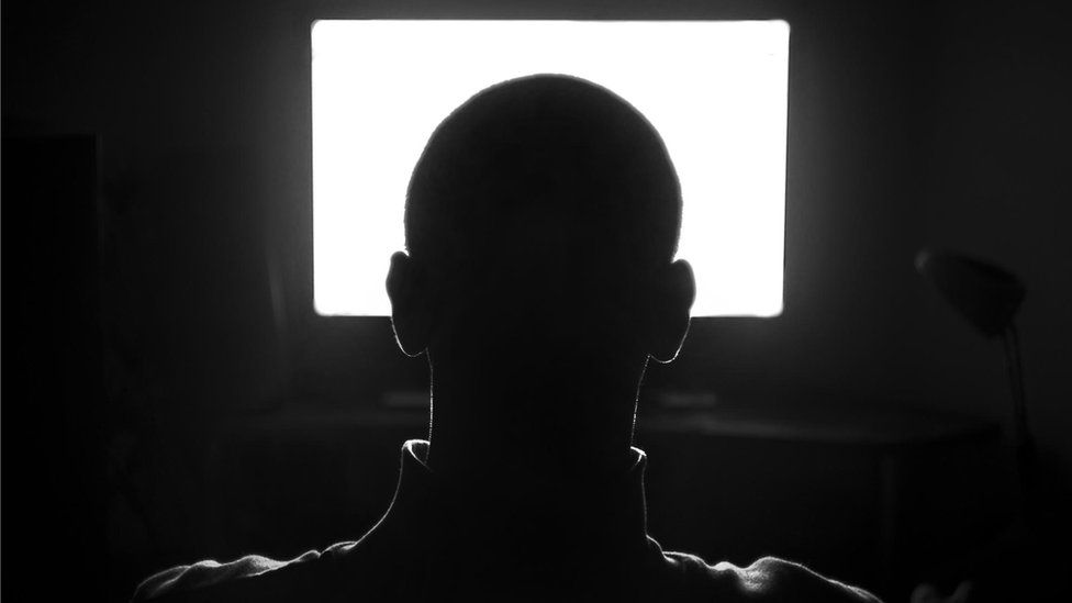 Silhoutted head watching a screen