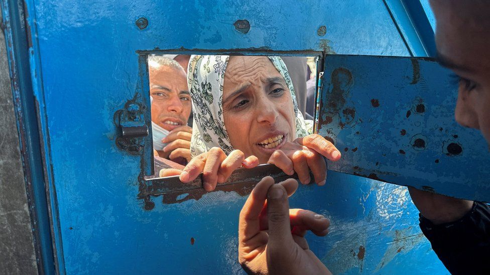 A Palestinian woman speaks with a worker as she waits to receive aid from an UNRWA distribution center which was hit in an Israeli strike, as the conflict between Israel and Hamas continues, in Rafah, in the southern Gaza Strip March 13, 2024
