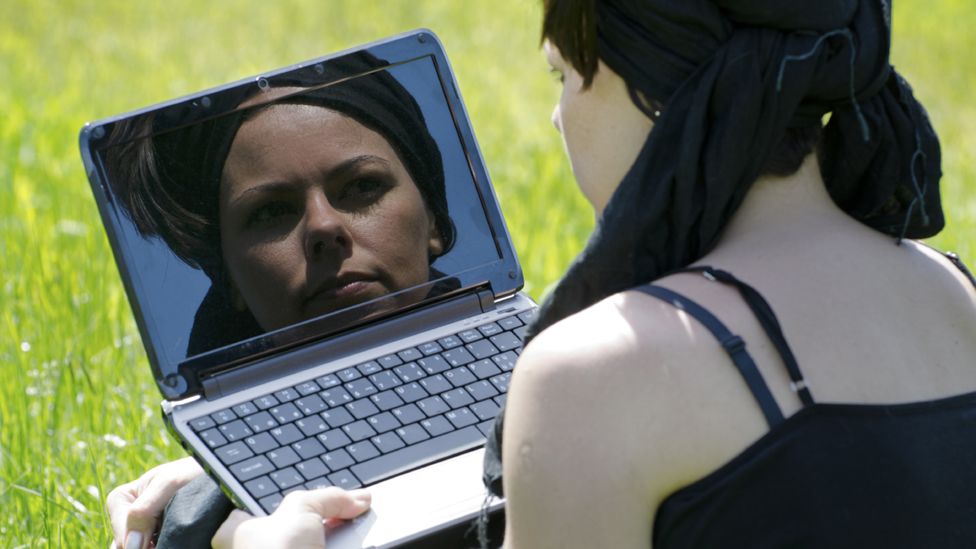 Woman looking at her reflection in computer