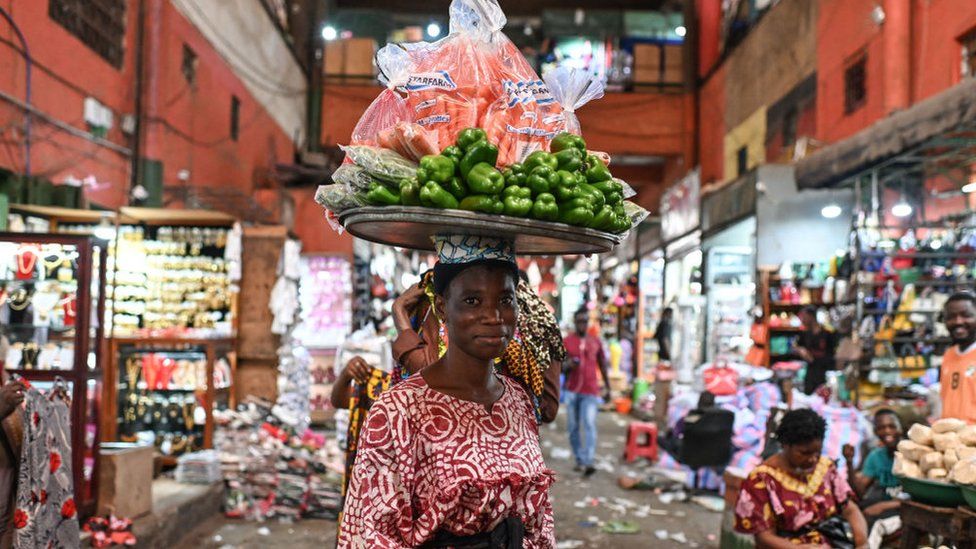 A street vendor carries vegetables on her head at the Adjame main market in Abidjan on March 7, 2024