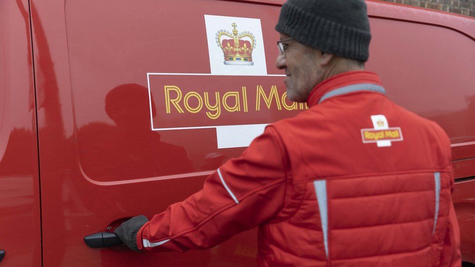 A Royal Mail worker in front of his van