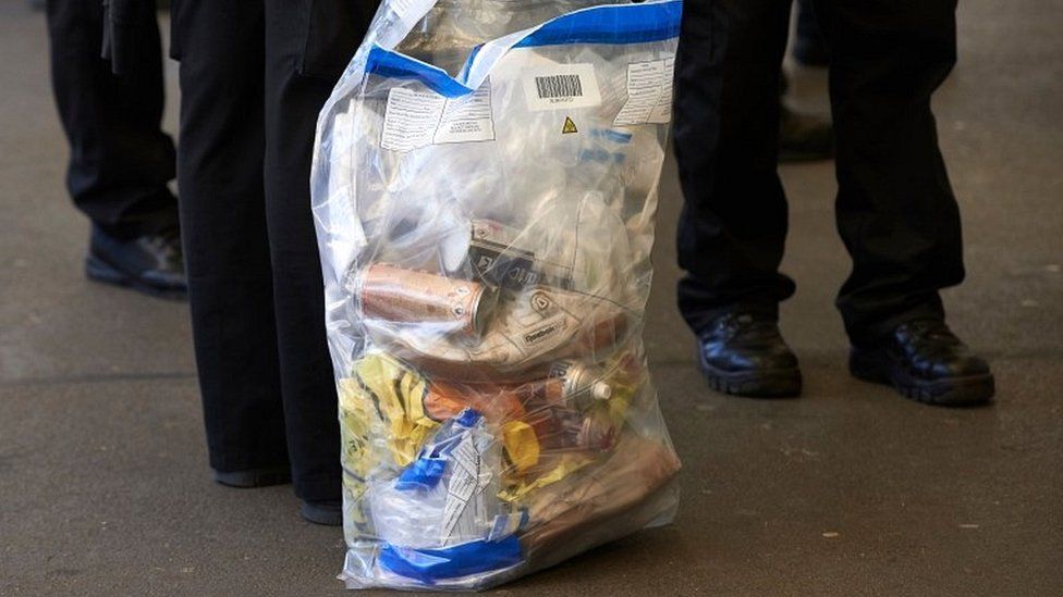 British Transport Police officers stand with evidence bags as they leave from Brixton train station in south London
