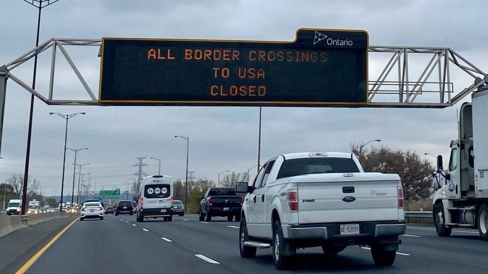 Traffic information board reading 'All Borders Crossings To USA Closed' is seen on Queen Elizabeth Way highway in Hamilton