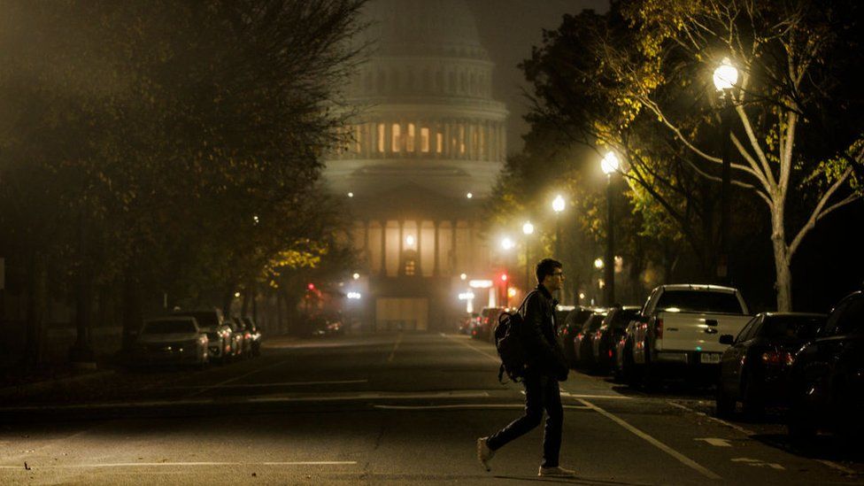 A man walking past Congress in the fog
