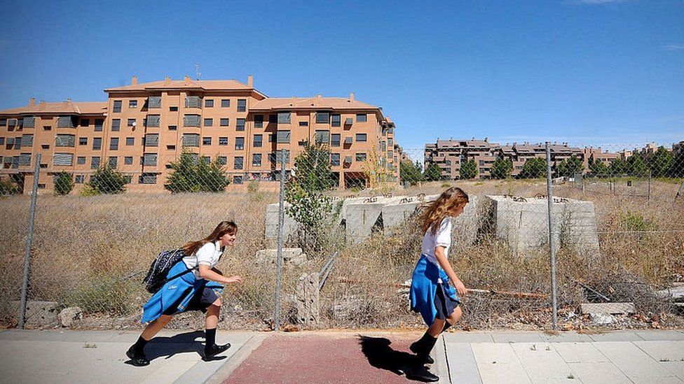 Two schoolgirls in front of unfinished apartment blocks in Valdeluz, Spain, in 2012