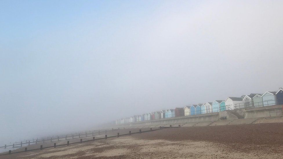 Beach huts shrouded in fog