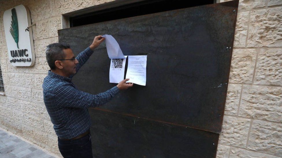 A man reads an Israeli military order posted on an iron door installed by soldiers at the entrance of the Union of Agricultural Workers Committees (UAWC) office in Ramallah, in the occupied West Bank (18 August 2022)