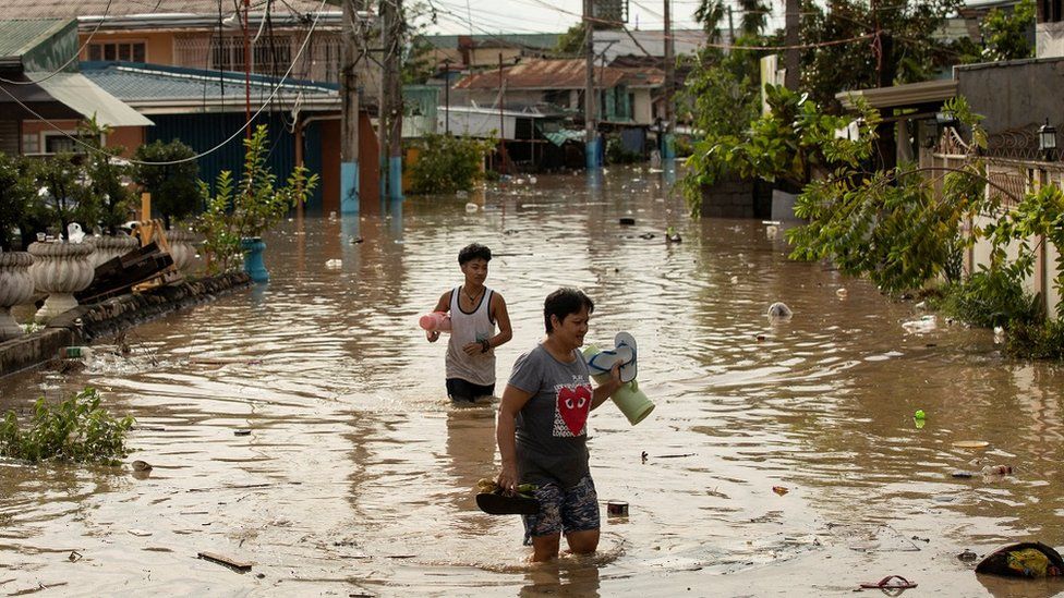 Residents wade through waist-deep flood waters after Super Typhoon Noru, in San Miguel, Bulacan province, Philippines, September 26, 2022.