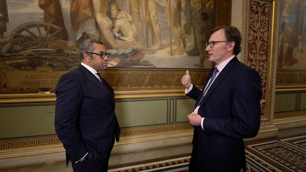 James Cleverly speaking with the BBC's James Landale in front of the mural