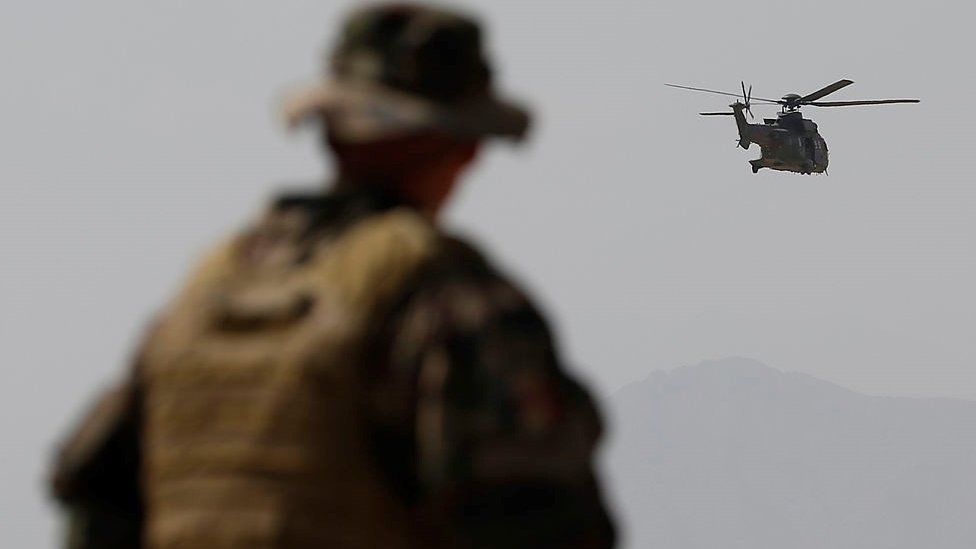 A French Army mentor looks on as a Eurocopter AS 532 Cougar helicopter of the French Helicopter Battalion 'Mousquetaire' flies