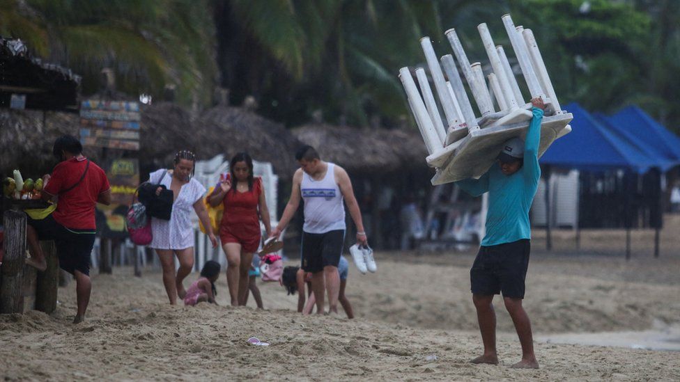 A man removes tables off a beach as Hurricane Otis barrels towards Acapulco