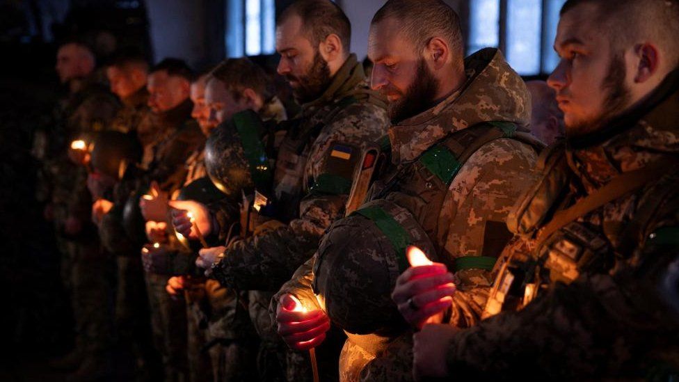 Ukrainian soldiers hold candles during a Christmas Eve service near the front line outside Kupiansk as Ukrainians celebrate their first Christmas according to a new calendar