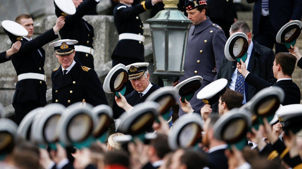 Britannia Royal Naval College officers raising their hats to the Prince of Wales.