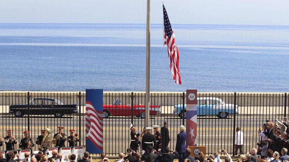 US flag being raised next to seafront
