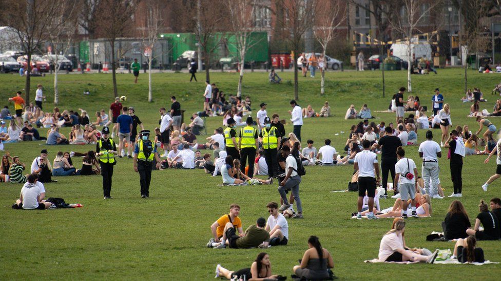 Police officers overlook people enjoying the warm weather at the Forest Recreation Ground in Nottingham.