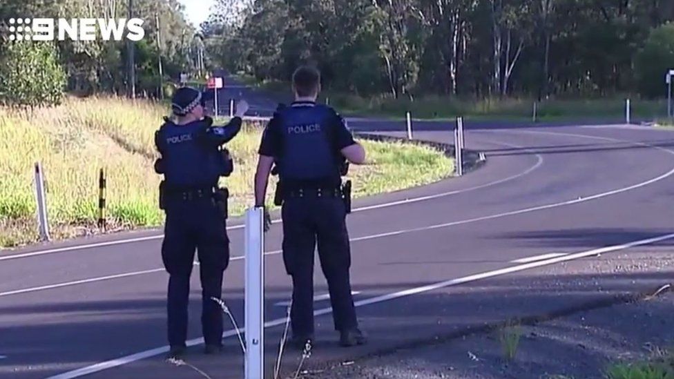 Two police officers stand at a roadblock in Queensland