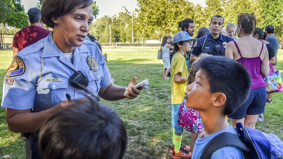 Pasadena police officers interview children by a tree that fell near the Kidspace Children's Museum in Pasadena, California on 28 July