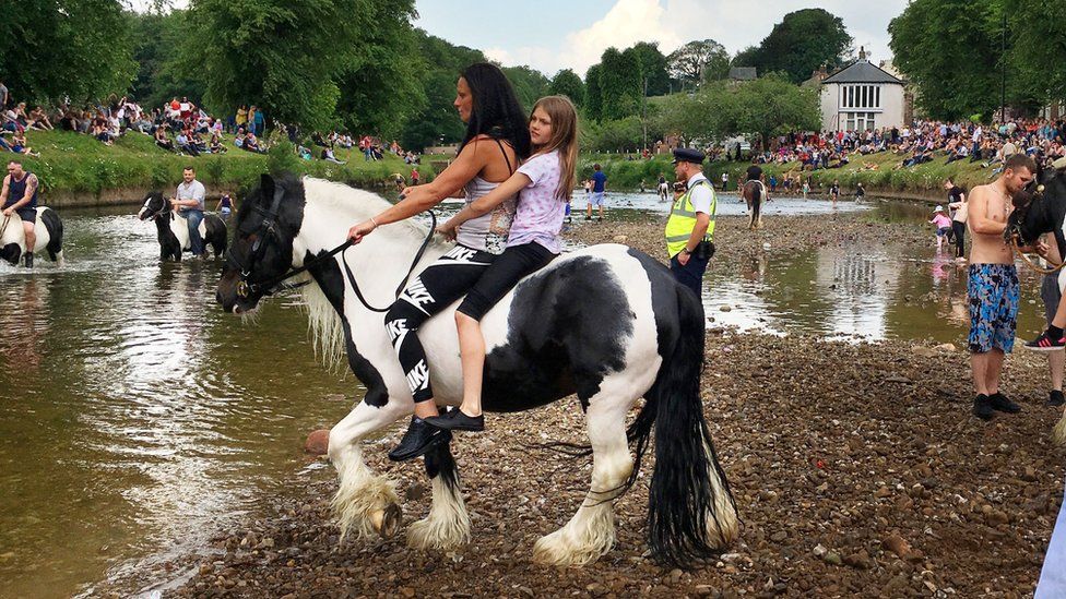 Girls ride a horse into the river