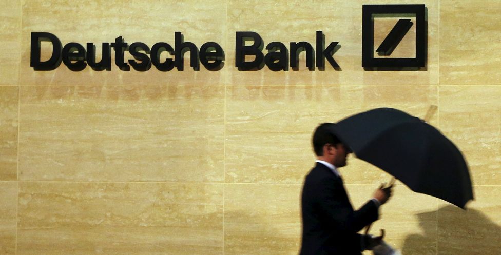 A man walks past Deutsche Bank's London offices carrying an umbrella