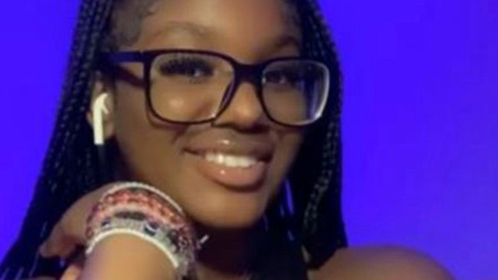 Elianne Andam, a young girl wearing glasses, in front of a purple background.