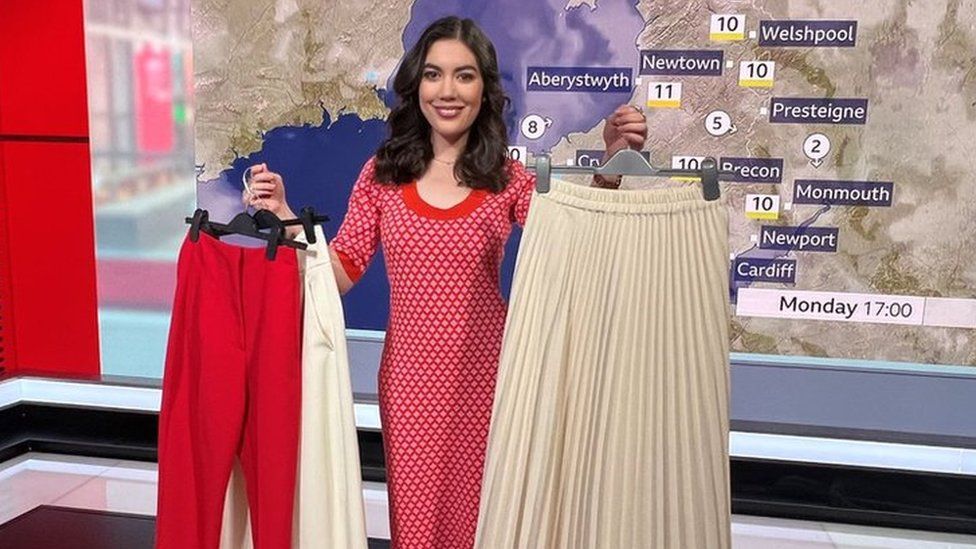 Sabrina holding up some of her clothes in the TV studio in front of a weather map