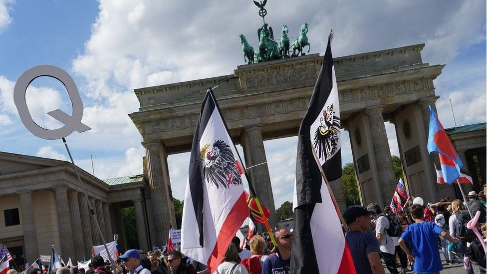 Men carry flags. including of the Kingdom of Prussia and the German Empire, at the Brandenburg Gate during protests against coronavirus-related restrictions and government policy on August 29, 2020 in Berlin, Germany