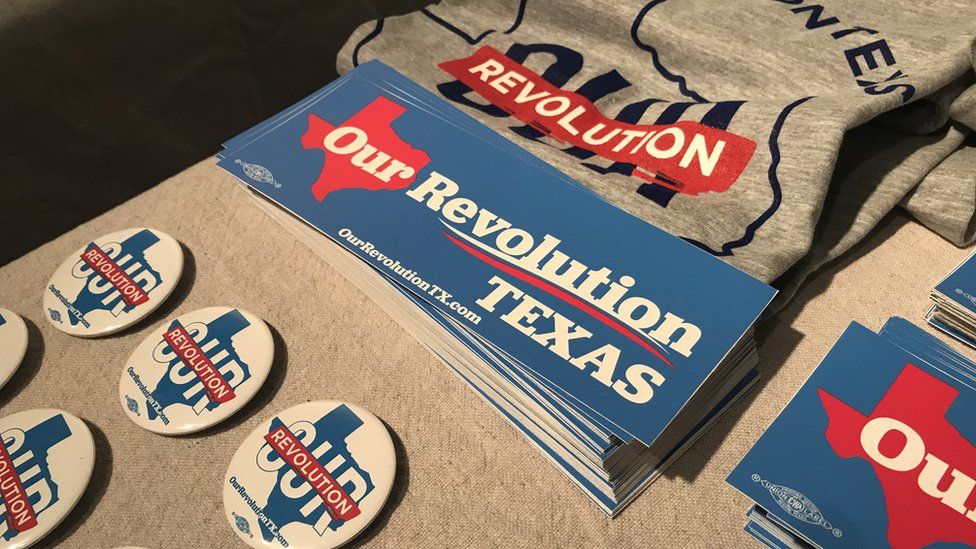 Our Revolution badges, bumper stickers and t-shirts lie on a table.