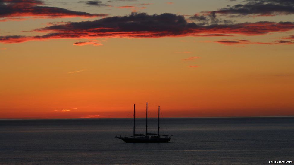 A sunset over the sea. A ship is on the water