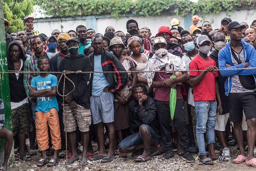 People watch the clearing of a building that collapsed during the earthquake in Brefet, a neighborhood in Les Cayes, Haiti, on 17 August 2021