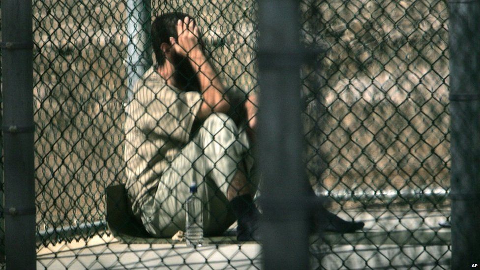 A detainee sits alone inside a fenced area during his daily outside period, at Camp 5 maximum security detention prison, Guantanamo Bay US Naval Base, Cuba, on 5 December 2006