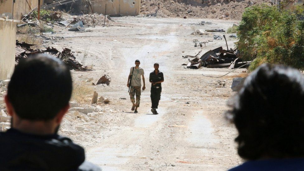 Rebel fighters walk by damaged buildings near Castello road in Aleppo, Syria, 16 September