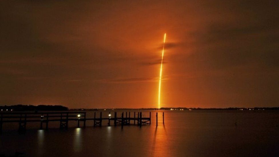 The SpaceX Falcon 9 launch appears in the distance from the back of River Rocks dockside restaurant along the Indian River, south of Rockledge, Florida (21 December 2015)