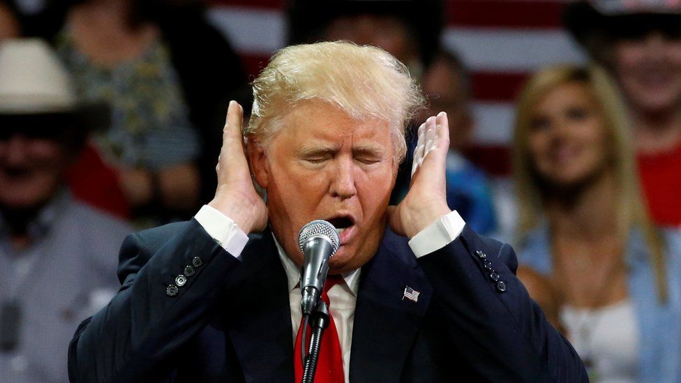 Donald Trump covers his ears during a campaign speech