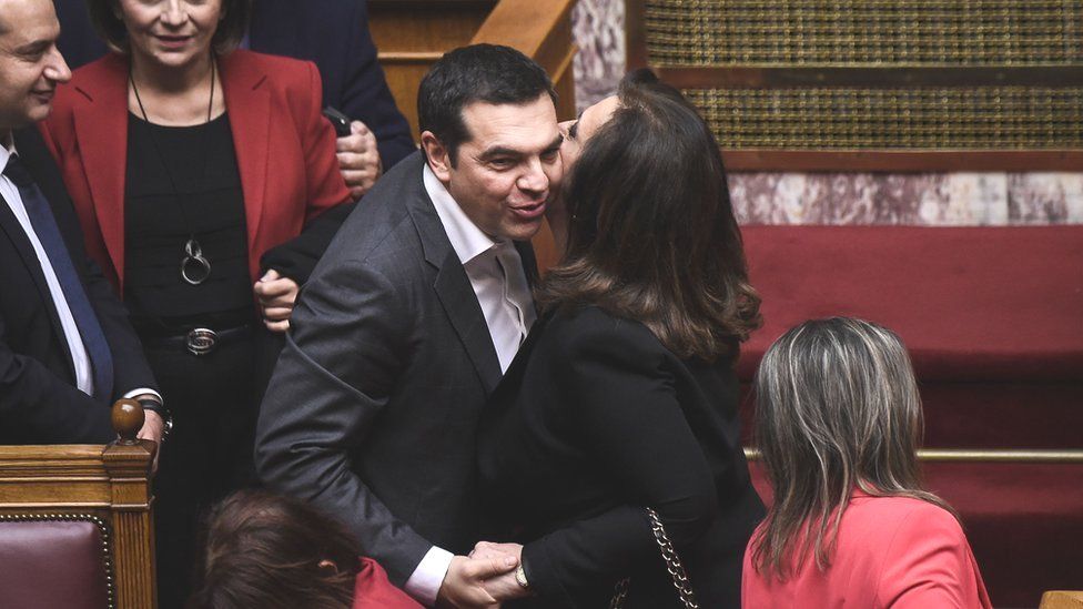 Alexis Tsipras (L) celebrates as he is congratulated following a voting session on the Prespa Agreement on 25 Jan