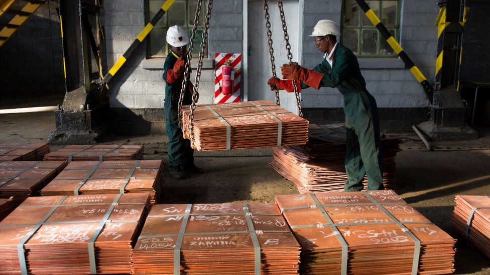 Workers move batches of copper sheets, which are stored in a warehouse and wait to be loaded on trucks on July 6, 2016 in Mufulira, Zambia